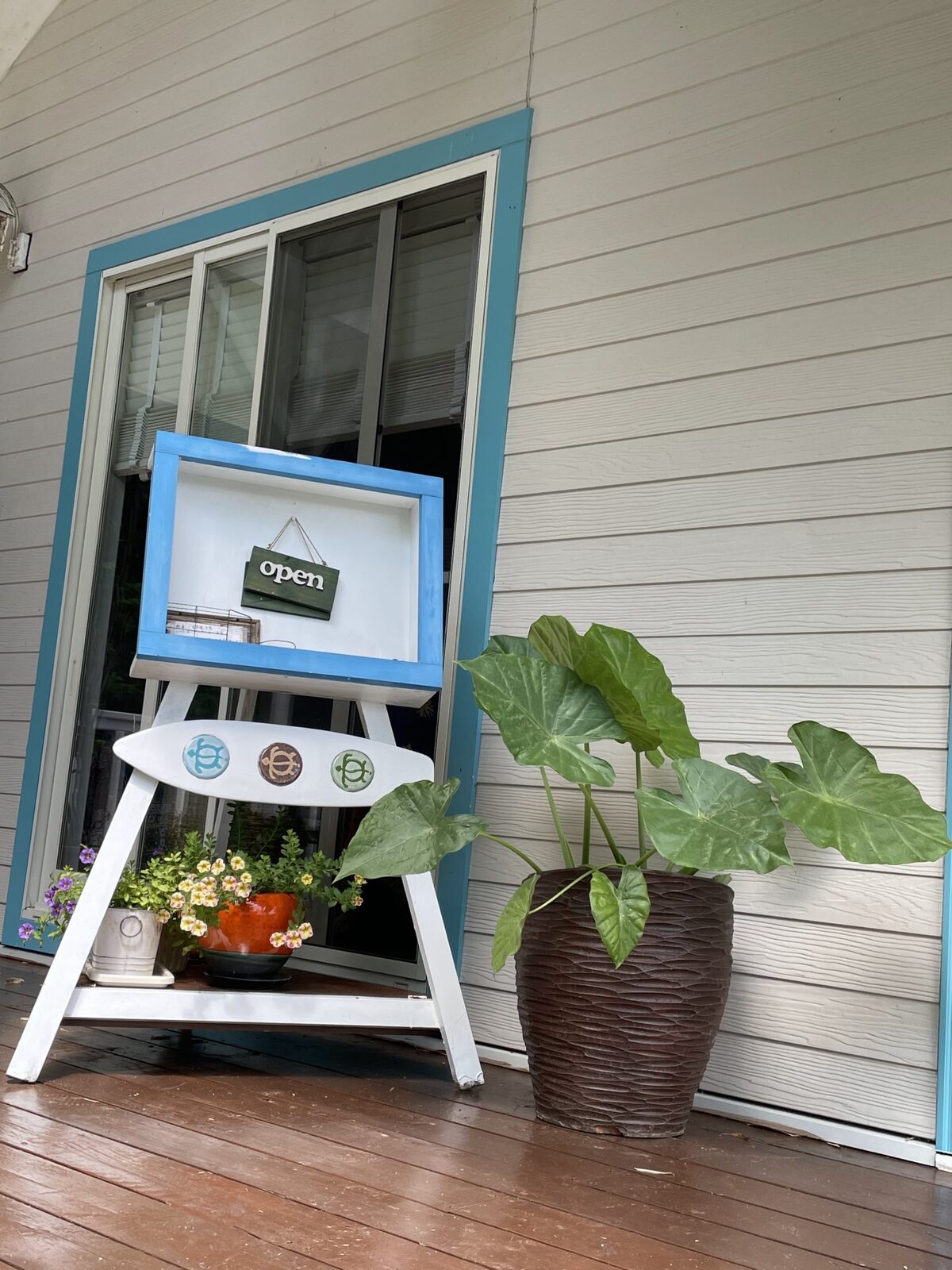 ポーチに掛けられた open の看板と観葉植物